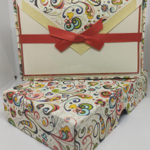 At the bottom part of the image, there's an exquisite box adorned with the captivating swirl design.On the top part of the image, you see the inside of the box. It contains a set of beautifully crafted cards and envelopes. The cards likely showcase the same mesmerizing swirl patterns or elegant designs that match the box, creating a harmonious visual experience