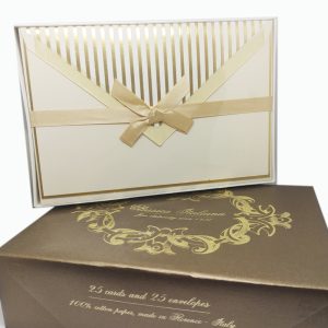 Elegant scene featuring two elements. At the bottom, there's a luxurious copper-gold box. On top of this regal box, there's another container, slightly smaller, which includes the set of 25 cards and 25 envelopes.