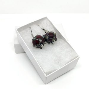 Deep burgundy earrings with unique glasswork, featuring tiny glass studs placed around the swirls of the sphere, similar to galaxies across the universe.