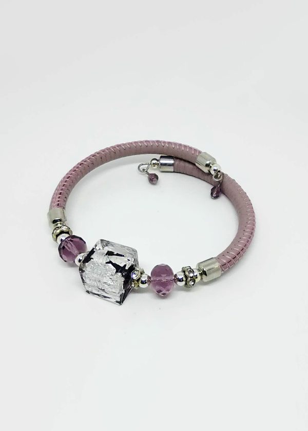 The bracelet features a clear glass centerpiece that encapsulates a delicate silver bead. On either side, a sequence of silver and light violet beads. Completing the ensemble is a refined pale pink leather band.