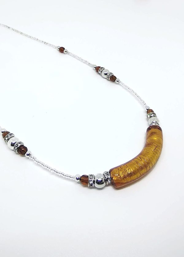 A necklace with a unique detail in the central golden blown glass pendant, featuring delicate sequences of dark gold and silver colored beads around the rest of the necklace.