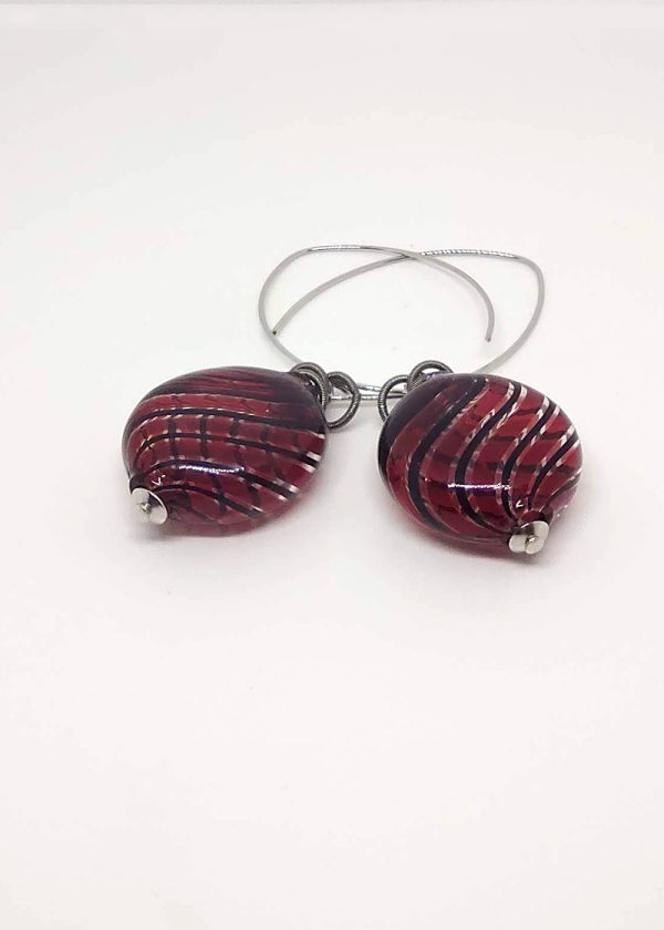 Detail of a glass drop earrings with a deep red and black lines beads and metal coil