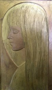 Wood relief of young girl in profile view. Long, carved hair with bangs.